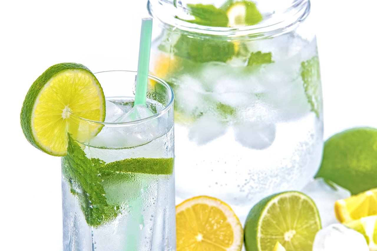 A refreshing glass of lime and mint infused water with ice, garnished with a slice of lime