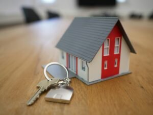 Miniature model of a house with keys on a table symbolizing real estate ownership or home buying